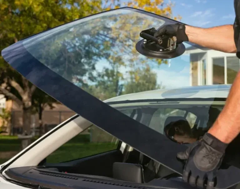 Technician positioning a car windshield with suction handles